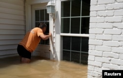 Patrice Laporte looks to see how much water is in his house surrounded by Harvey floodwaters in Houston, Texas, Sept. 1, 2017.