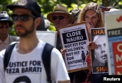 Protesters react as they hold placards and listen to speakers during a rally in support of refugees in central Sydney, Australia, Oct. 19, 2015.