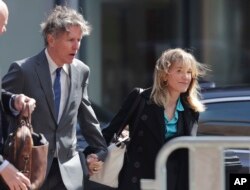 FILE - Actress Felicity Huffman arrives holding hands with her brother Moore Huffman Jr., left, at federal court in Boston, Massachusetts, April 3, 2019, to face charges in a nationwide college admissions bribery scandal.