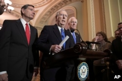FILE - Senate Majority Leader Mitch McConnell, R-Ky., flanked by Sen. John Barrasso, R-Wyo., left, and Majority Whip John Cornyn, R-Texas, speaks to reporters about efforts to avoid a government shutdown this weekend, at the Capitol in Washington, Jan. 17, 2018
