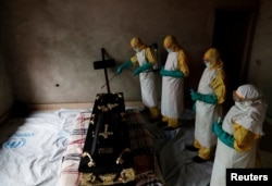 A healthcare worker sprays a room during a funeral of Kavugho Cindi Dorcas who is suspected of dying of Ebola in Beni, North Kivu Province of Democratic Republic of Congo, Dec. 9, 2018.
