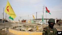 FILE - A soldier of the Kurdish Democratic Party patrols at a destroyed roundabout in the town of Snuny, close to Sinjar, northern Iraq, Jan. 29, 2015.