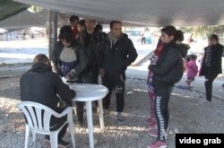 As migrants streamed into the Karatepes registration camp Saturday on the Greek island of Lesbos, many smiled as they clutched bags, suitcases and the hands of small children. It is their first stop after what was for many a harrowing boat ride from Turke