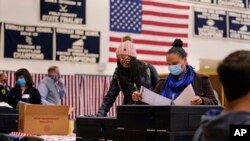 Two women, wearing protective masks due to the COVID-19 pandemic, cast their ballots at a polling station at Windham High School in Windham, New Hampshire, on Nov. 3, 2020.