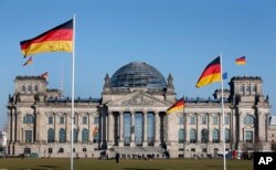FILE - In this March 5, 2013 file photo German flags fly in front of the Reichstag building, host of the German Federal Parliament Bundestag, in Berlin, Germany.