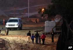 FILE - Migrants traveling with children walk up a hill to a waiting U.S. Border Patrol agent just inside San Ysidro, California, after climbing over the border wall from Playas de Tijuana, Mexico, Dec. 3, 2018.
