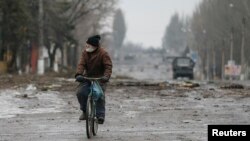 A local resident rides his bicycle along a street in Vuhlehirsk, Donetsk region, Feb. 6, 2015.