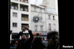 Journalists work outside a restaurant where bullet impacts are seen the day after a series of deadly attacks in Paris, France, Nov. 14, 2015.