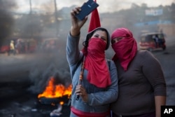 Masked supporters of presidential candidate Salvador Nasralla take a selfie at a burning roadblock set up by demonstrators protesting what they call electoral fraud in Tegucigalpa, Honduras, Dec. 1, 2017.