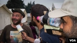 Questions are posed not just to fellow refugees, but also to NGO workers, volunteers and journalists at the camp (J. Owens/VOA).