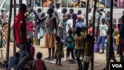 At Ocea Reception Center, Yumbe district, women and children refugees stand in line waiting to board an UNHCR bus for relocation to Bidibidi settlement. (N. Jidovanu/VOA)