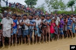 Rohingya Muslim men, who crossed over from Myanmar into Bangladesh, wait for their turn to collect food items distributed by aid agencies in Balukhali refugee camp, Bangladesh, Sept. 19, 2017.