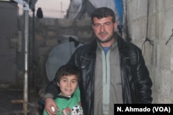 Hoger, a Yazidi boy taken by IS with his mother and siblings from Sinjar in 2014, stands beside his orphanage housefather Rami Qaddor in Atmeh camp for refugees in northern Syria.