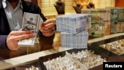 FILE - A man counts U.S. dollars at a currency exchange office in Tripoli, Libya, April 24, 2016. More countries are adding the yuan to their foreign reserves, but the U.S. dollar still dominates.