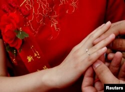 Pengantin pria asal Provinsi Hebei di China, memasang cincin kawin ke jari pengantin perempuan, dalam kawin massal di Seoul, Korea Selatan, 20 September 2006. (Foto: Reuters)