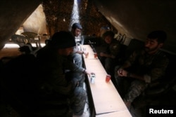 FILE - Fighters of the Syria Democratic Forces drink tea as they rest inside a shelter in northern province of Raqqa, Syria.