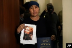 In this Dec. 6, 2018, photo, Nurbakyt Kaliaskar, the wife of a sheep herder, holds up a picture of her daughter, Rezila Nulale, and her graduation certificate, at an office of an advocacy group for ethnic Kazakhs born in China in Almaty, Kazakhstan.