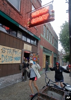Two women who were riding out the storm dance to the music outside the Barbary Coast bar in downtown Wilmington, N.C., as Hurricane Florence threatens the coast, Sept. 13, 2018.