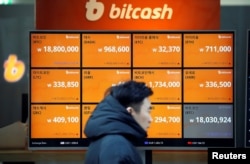 A man walks past an electric board showing exchange rates of various cryptocurrencies including Bitcoin (top-L) at a cryptocurrencies exchange in Seoul, South Korea, Dec. 13, 2017.