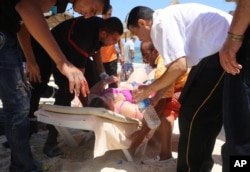 FILE - Injured people are treated after gunmen opened fire at beach near the Imperial Marhaba hotel in Sousse, Tunisia, June 26, 2015.