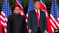 FILE - U.S. President Donald Trump, right, meets with North Korean leader Kim Jong Un on Sentosa Island, in Singapore, June. 12, 2018. North Korea warned Friday it could revive a state policy aimed at strengthening its nuclear arsenal if the United States