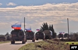 FILE - An image grab taken from AFP-TV shows Russian army vehicles on patrol in the area of Arimah, just west of Manbij, Syria, Jan. 17, 2019.
