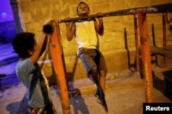 A boy does pull-ups from a metal bar outside the Luta pela Paz (Fight for Peace) boxing school, in the Mare favela of Rio de Janeiro, Brazil, June 2, 2016.
