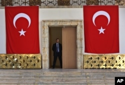 FILE - A Turkish parliament security man stands guard next to the broken yellow copper doors laid on the ground at the entrance of the assembly hall at the parliament building, which was attacked by Turkish warplanes during the failed military coup on July 15 in Ankara, Turkey, July 19, 2016.