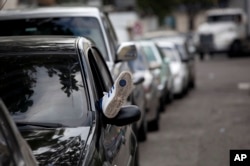 FILE - A man rests in his car while in line outside the Duncan car battery store in Caracas, Venezuela, Aug. 6, 2015.