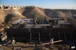 Palestinian laborers work at a construction site in a new housing project in the Israeli settlement of Maale Adumim, near Jerusalem, Feb. 7, 2017.