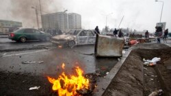 People walk past cars, which were burned after clashes, on a street in Almaty, Kazakhstan, Jan. 7, 2022.
