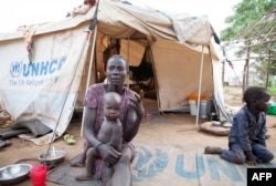 FILE - A woman and her children displaced by fighting in South Sudan sit outside her tent at the Kule camp for Internally Displaced People at the Pagak border crossing in Gambella, Ethiopia, July 10, 2014.