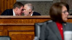 Sen. Mark Warner, D-Va., left, and Sen. Thom Tillis, R-N.C., center, speak together as Treasury Secretary Janet Yellen and Federal Reserve Chairman Jerome Powell testify during a Senate Banking Committee hearing on Capitol Hill, Nov. 30, 2021.