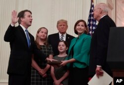 President Donald Trump, center, listens as retired Supreme Court Justice Anthony Kennedy, right, ceremonially swears-in Supreme Court Justice Brett Kavanaugh, left, in the East Room of the White House in Washington, Oct. 8, 2018.