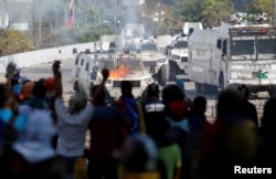 Opposition supporters react in front of a burning military vehicle during a rally against the government of Venezuela's President Nicolas Maduro in Caracas, Venezuela, May 1, 2019.