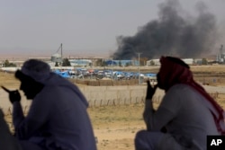 Jordanian residents of Jabir village watch aid deliveries to Syrians fleeing government offensive in the south as smoke from unknown fire rises, July 3, 2018.