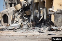 FILE - Libyan forces allied with the U.N.-backed government walk through a destroyed building during a battle with Islamic State militants in Sirte, Libya, Oct. 2, 2016.
