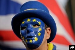 An anti-Brexit demonstrator wears a mask bearing the stars of the European flag, during a protest outside the houses of Parliament, in London, Dec. 19, 2018.