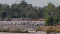 FILE - A fishing boat passes near a construction site of the Don Sahong dam, near the Cambodia-Laos border, June 20, 2016.