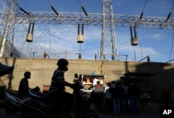 FILE - Commuters drive past the power transmission towers installed inside the International Tech Park, which houses several information technology companies in Bangalore, India, Sept. 26, 2015.