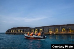 Aktivis Greenpeace menulis Coral not Coal di lambung tongkang batubara di Karimunjawa. (Foto: Greenpeace Indonesia)