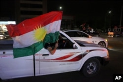 \Iraqi Kurdish men celebrate as they wave Kurdish flags in the streets after the polls closed in the controversial Kurdish referendum on independence from Iraq, in Irbil, Iraq, Sept. 25, 2017.