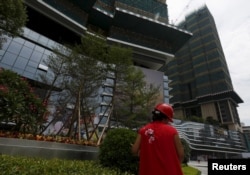 FILE - A cleaner at work outside a new luxury apartment tower under construction in the southern Chinese city of Shenzhen, Aug. 28, 2015.