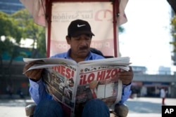 A man having his shoes shines reads a newspaper whose front page declares "He did it!" over a picture of U.S. President Donald Trump holding up signed documents, as he took action to jumpstart construction on a promised border wall, in Mexico City, Jan. 26, 2017.