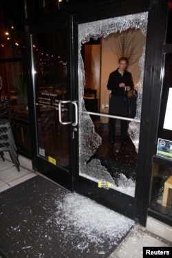 A man looks at broken glass after a riot swept through the area in protest to the election of Republican Donald Trump as President of the United States in Portland, Oregon, Nov. 10, 2016.