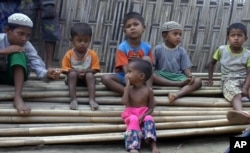 In this March 17, 2017, image made from video, Rosmaida Bibi, center foreground, suffering from severe malnutrition, sits on a pile of bamboo trees with other children at the Dar Paing camp, north of Sittwe, Rakhine state, Myanmar.