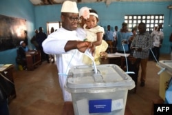 Sierra Leone's People Party presidential candidate Julius Mada Bio holds his daughter while casting his ballot for the general elections, at a polling station in Freetown, March 7, 2018.