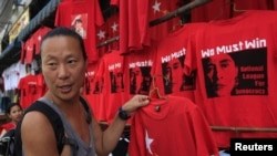 A Korean tourist buys a tee-shirt at a shop in Rangoon on March 29, 2012.