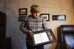 FILE - Zia Ghafoori displays the Purple Heart at his home in Charlotte, N.C., that he received while working with U.S. Forces in Afghanistan, Dec. 16, 2019. He received a Special Immigrant Visa in 2014 and is working toward becoming a U.S. citizen.