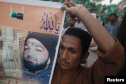 A supporter of a religious political party holds a banner of convicted killer Mumtaz Qadri during a demonstration against Qadri's sentence, in Karachi, Pakistan, March 9, 2015.